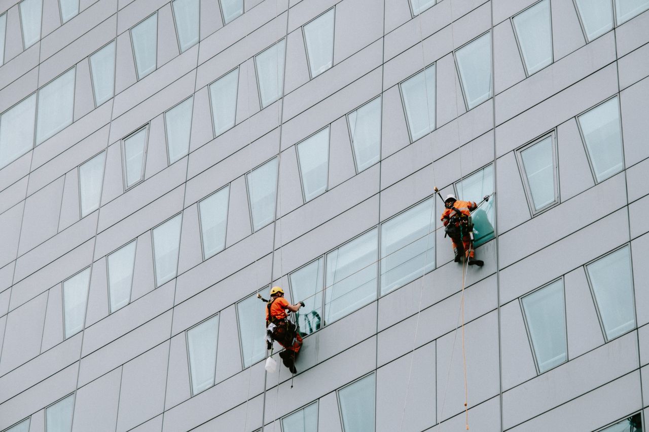 Window cleaners equipped with safety gear working on a skyscraper’s facade.